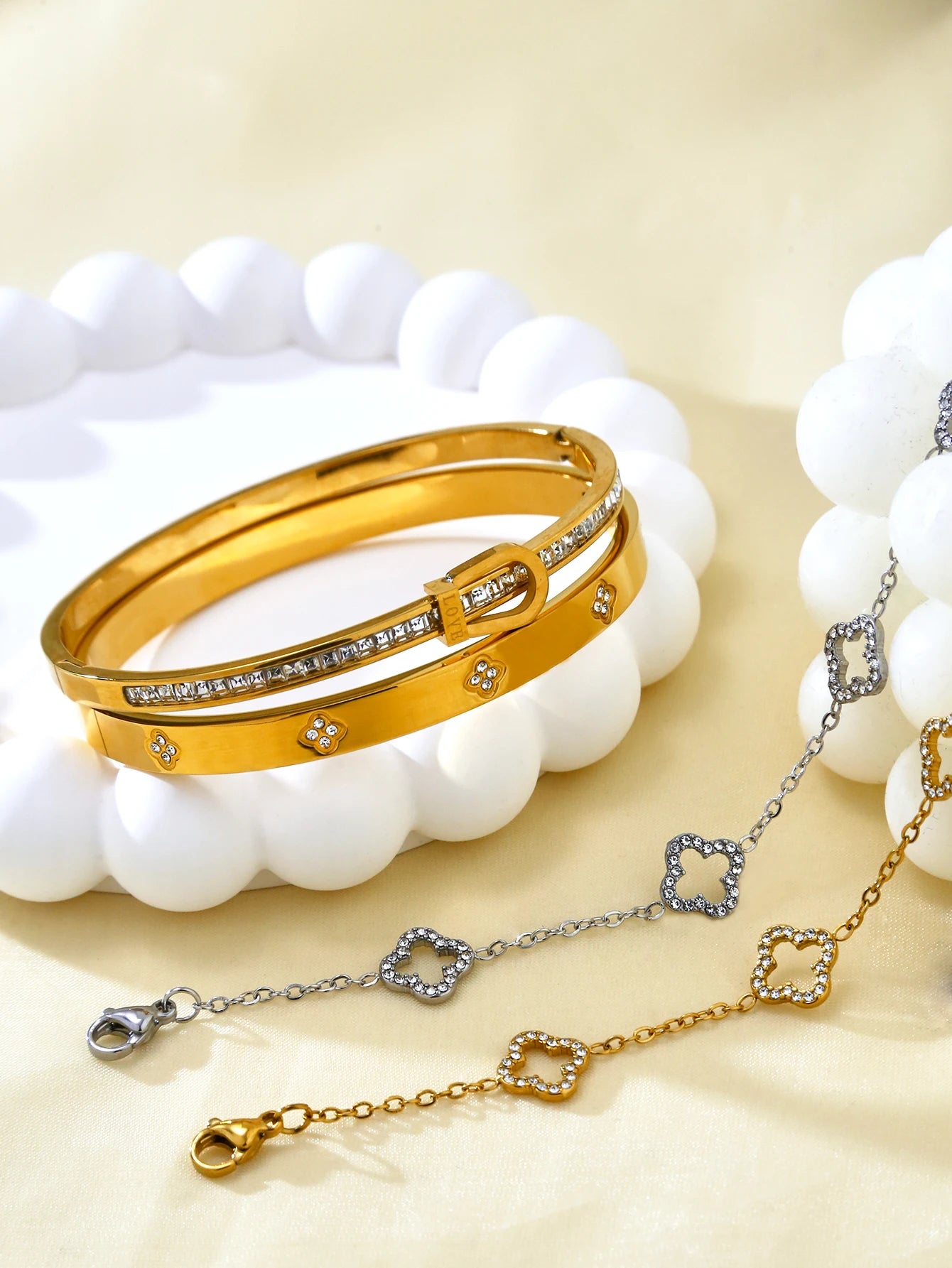 Luxury Clover Bracelet for Women auf einer eleganten Unterlage, gold und silberne Armbänder mit Glitzersteinen.